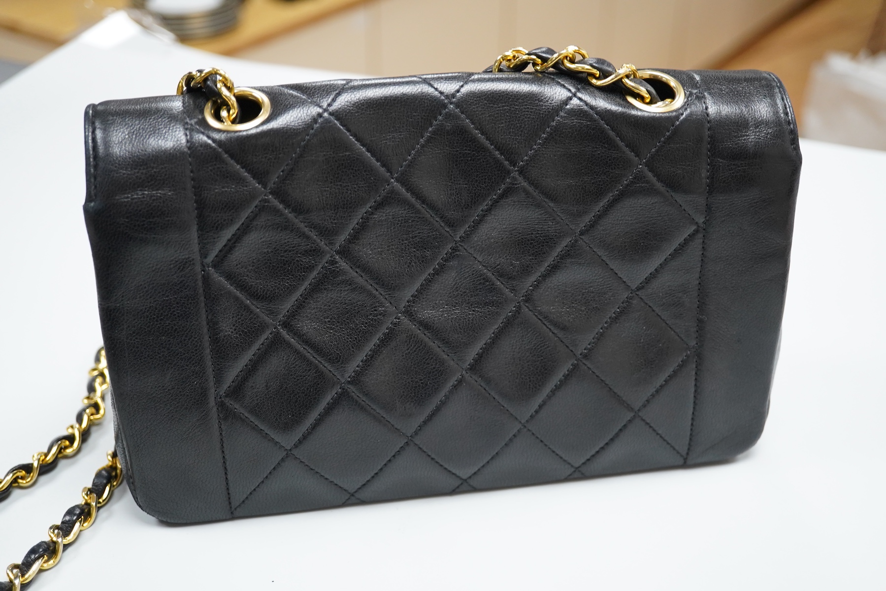 A late 1980’s Chanel black leather Diana shoulder bag with original dust cover and bag, Chanel authenticity card numbered 1944645, interior date code rubbed, 23cm wide, Provenance: Purchased by the vendor, 26 Old Bond St